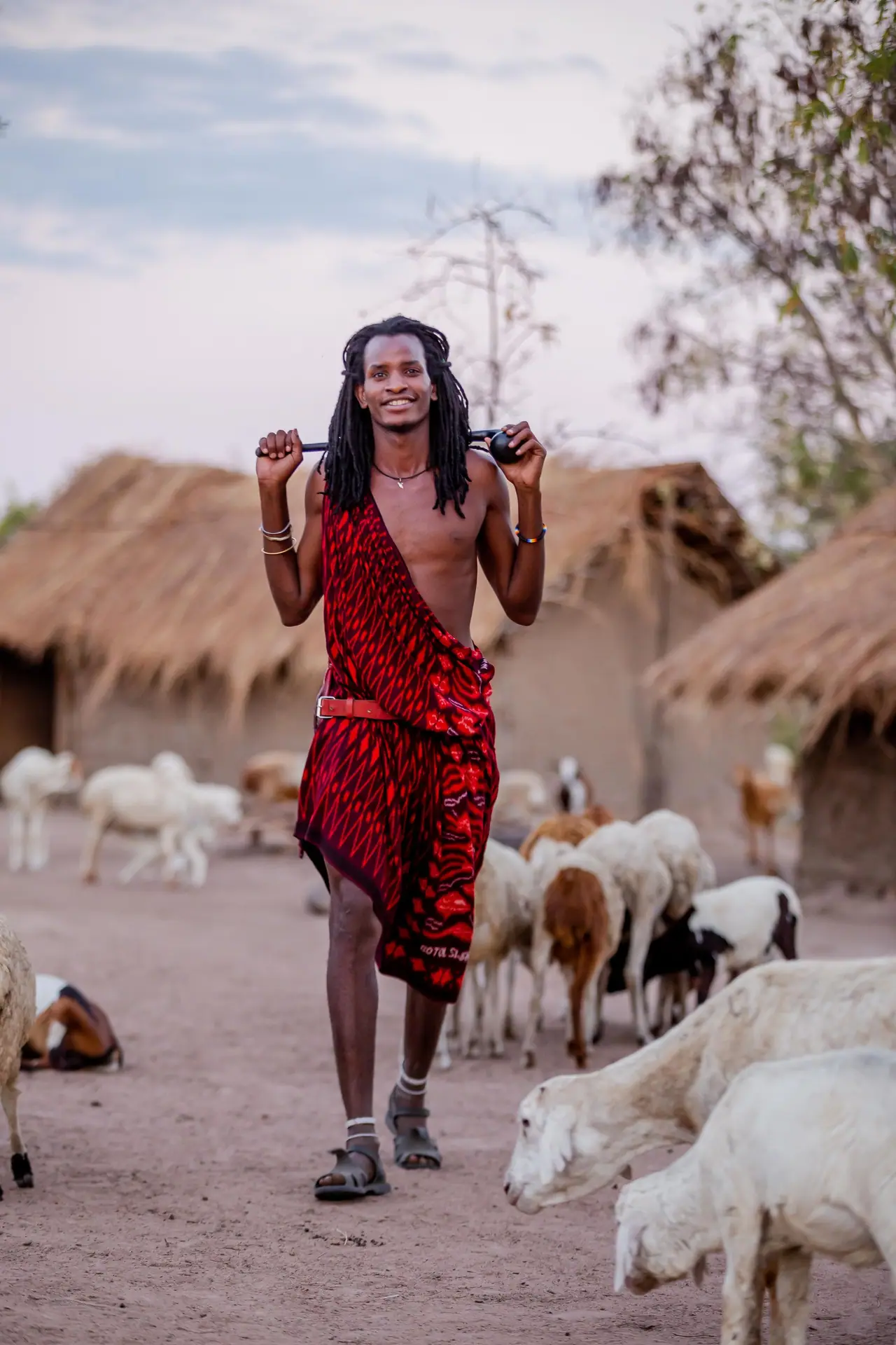 A Maasai man among goats outside a village home